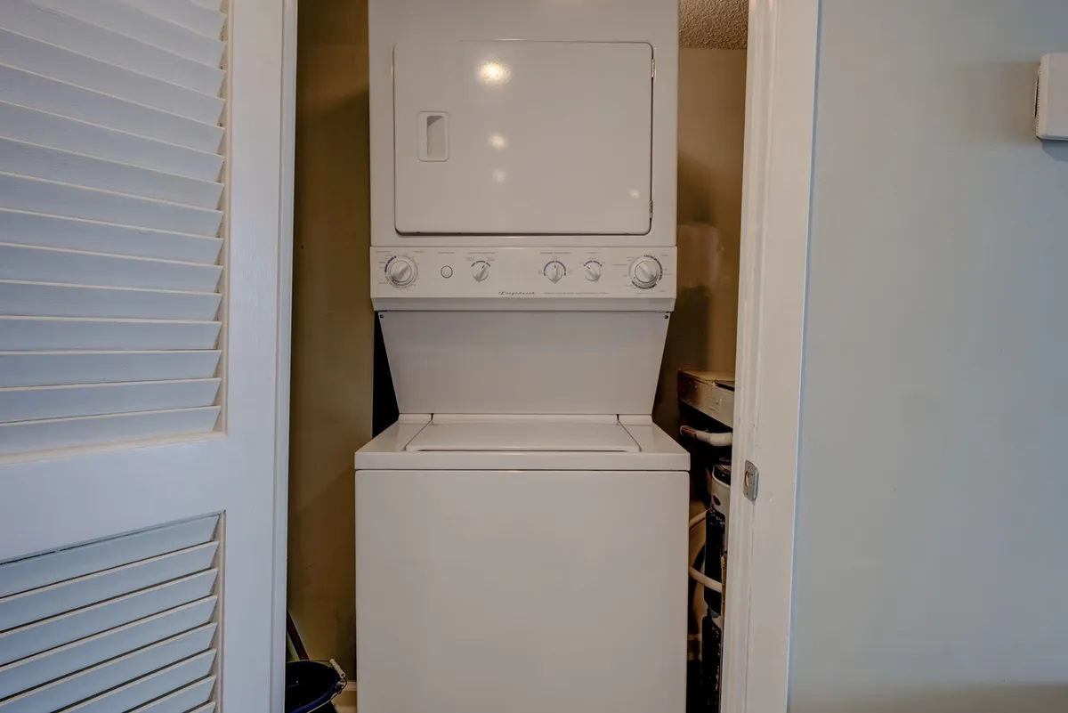 A compact laundry area with a stacked washer and dryer behind closet doors, emphasizing in-unit convenience and practical storage.