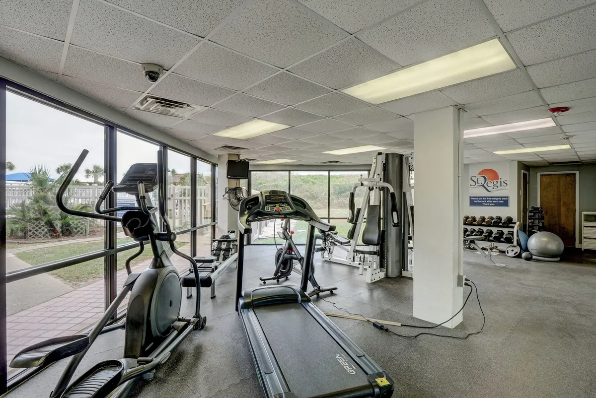 A bright, energetic fitness center with a treadmill, elliptical, strength training equipment, and large windows that let in natural light. The inviting atmosphere encourages an active lifestyle and wellness-focused routines.