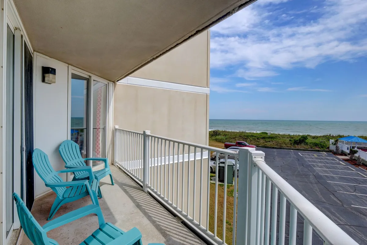 A tranquil balcony scene with Adirondack chairs facing the ocean, offering a peaceful place to relax, socialize, or take in stunning views. The outdoor setting highlights the property’s proximity to the water and easy access to the beach.