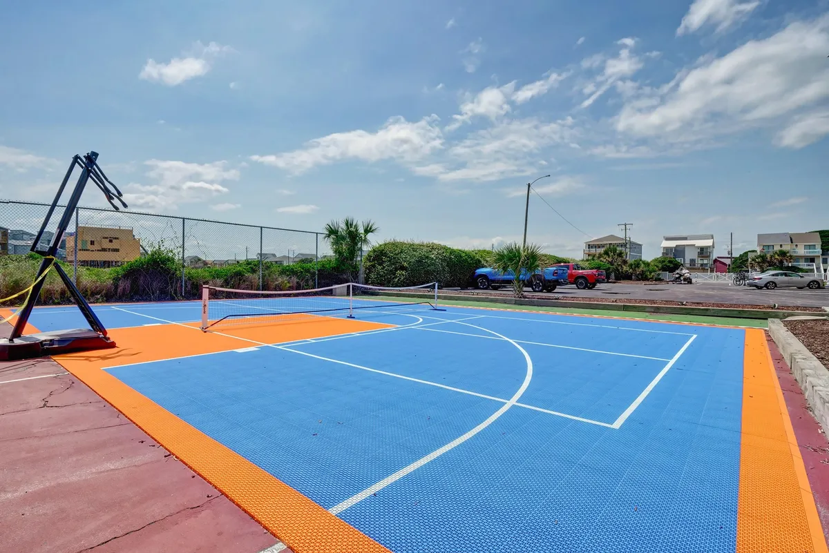 This exterior image features an outdoor basketball court with a visible tennis net and lush greenery surrounding the area. The space is clearly designed for active recreation and group activities, supporting friendly competition and outdoor fun.