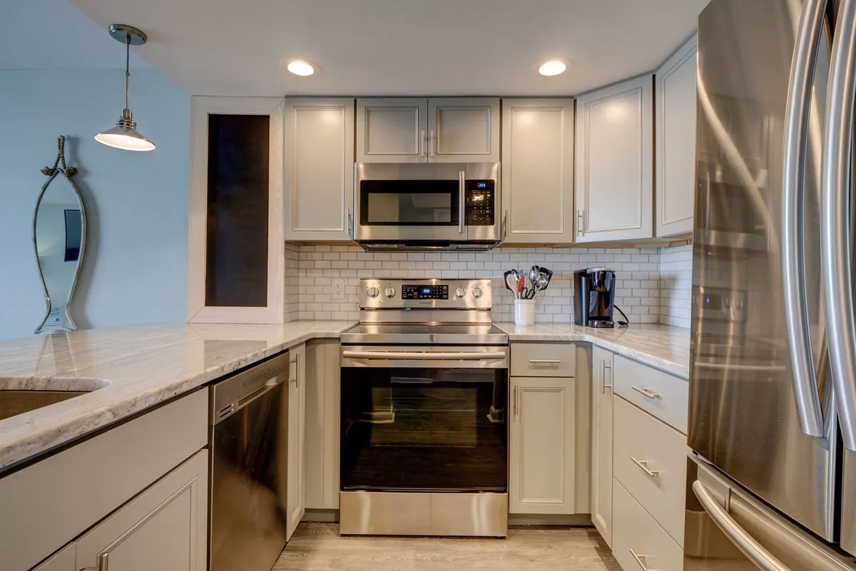 A modern kitchen with stainless steel appliances, a granite countertop, and a white tile backsplash. The space is clearly designed for cooking and socializing, with ample room for family and friends to prepare meals together.