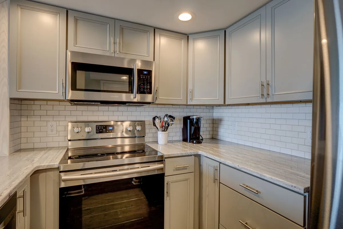 A modern kitchen with sleek stainless steel appliances, a granite countertop, a white subway tile backsplash, and an assortment of kitchen utensils. The space is designed for both cooking and entertaining, offering ample storage and work surfaces.